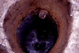 写真：井戸枠のない素掘りの井戸。土器が見えている。
