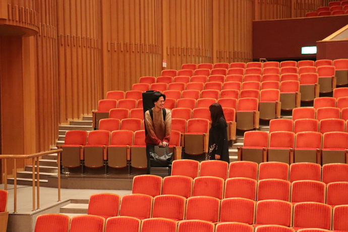 写真:ホールの通路で初めて顔合わせ笑顔とあいさつを交わす宮本さんと多田さん